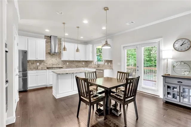 a open dining room with stainless steel appliances kitchen island granite countertop a stove a sink a refrigerator with a dining table and chairs with wooden floor