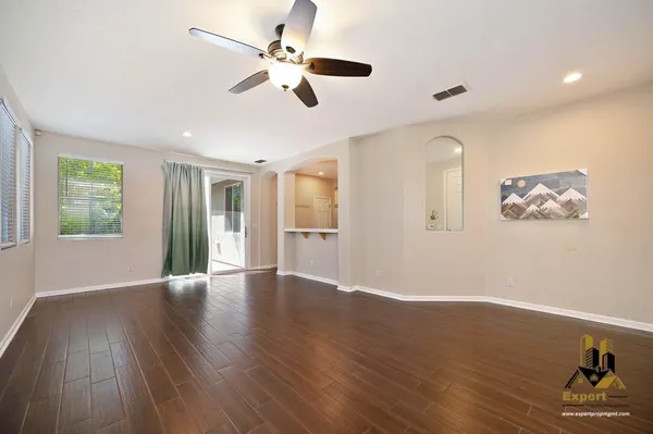 a view of an empty room with wooden floor and a window