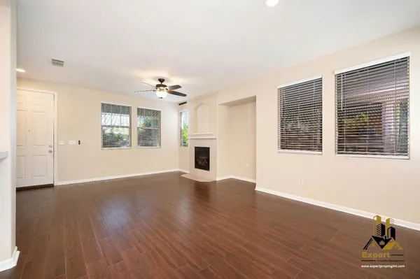 a view of an empty room with a window and wooden floor