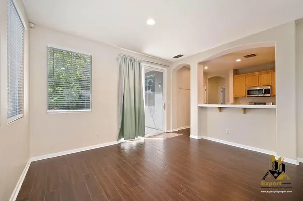 a view of an empty room with wooden floor and a window