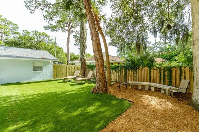 a view of a backyard with wooden fence and a large tree