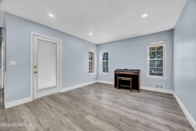 an empty room with windows a fireplace and wooden floor