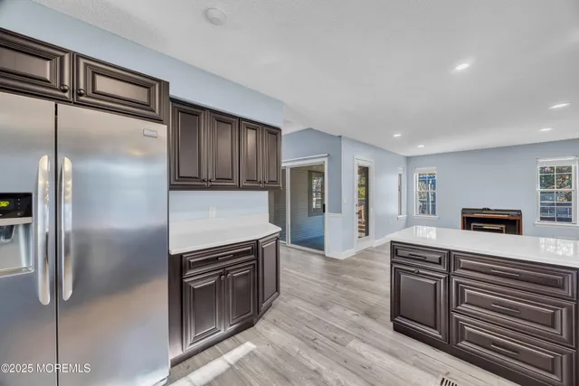 a kitchen with stainless steel appliances granite countertop a refrigerator a stove and a sink with wooden floor