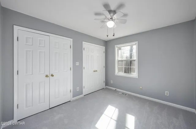 a view of an empty room with wooden floor and bathroom