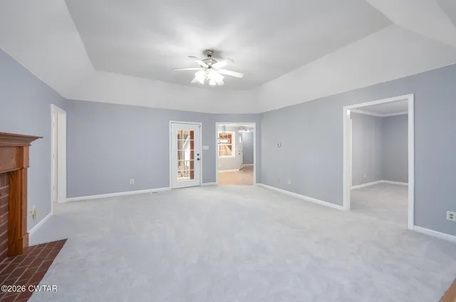 a view of an empty room with a chandelier fan