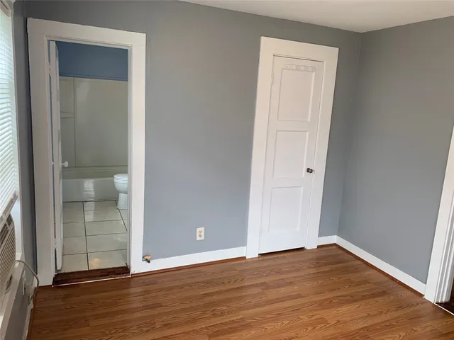 an empty room with wooden floor & closet area