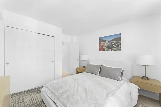 a bedroom with a bed and a lamp on the dresser