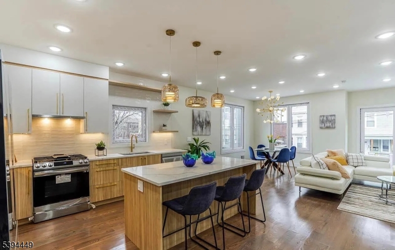 376 21st Street Irvington, NJ 07111 - Photo 3 of 24 a kitchen with stainless steel appliances kitchen island granite countertop a stove a sink and a dining table with wooden floor