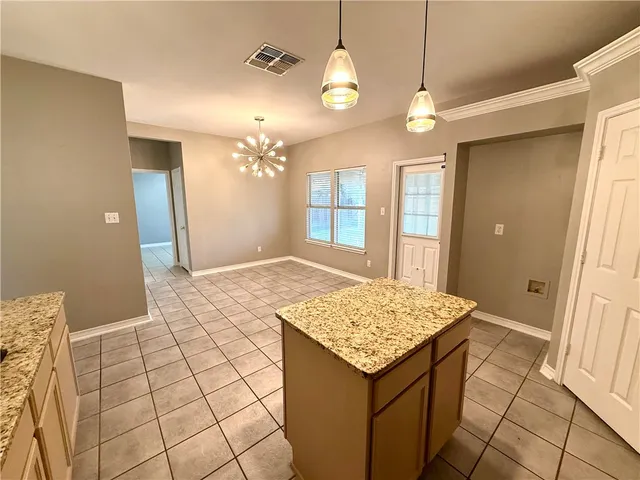 a view of kitchen with granite countertop cabinets and chandelier