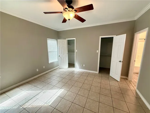 a view of an empty room with window and chandelier fan