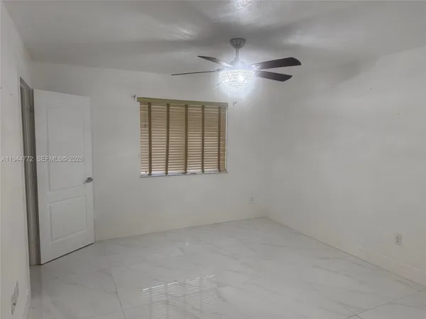 an empty room with a chandelier fan and windows