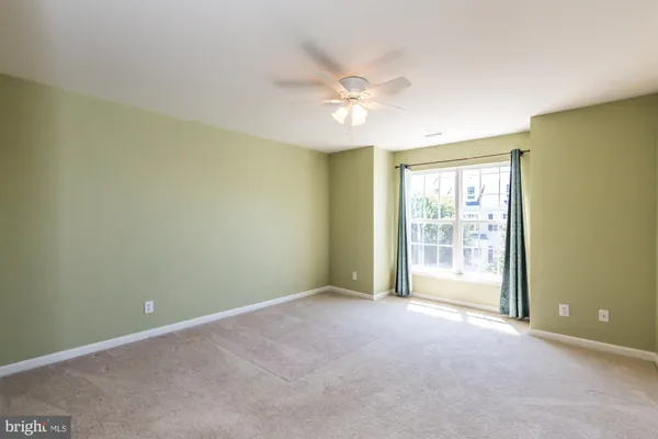 an empty room with chandelier fan and windows