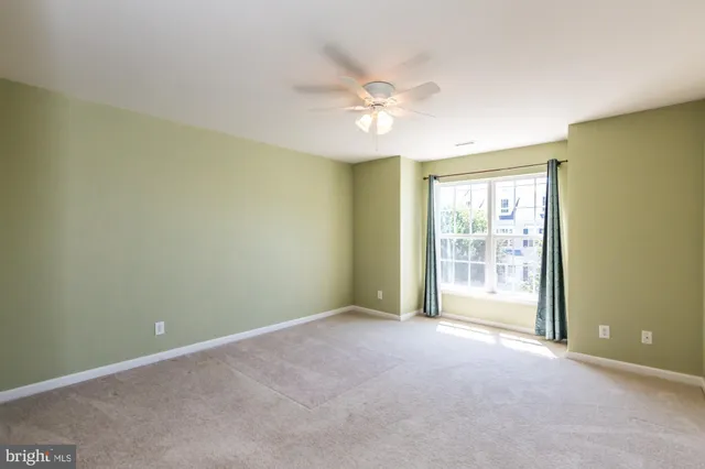 an empty room with chandelier fan and windows