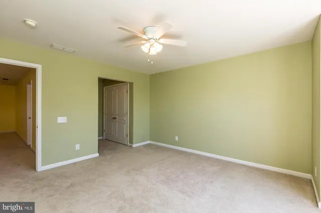 an empty room with a chandelier fan and a bathroom