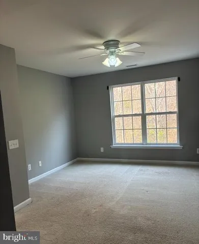 a view of an empty room and chandelier fan