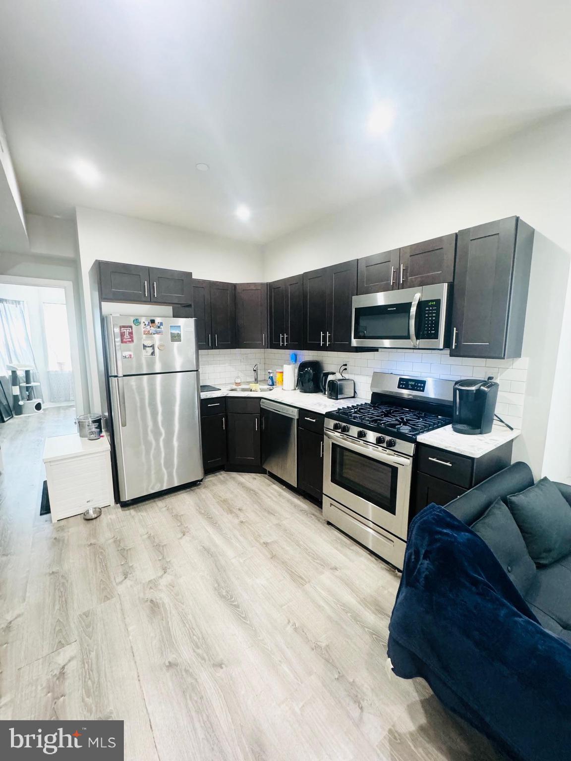 2327 Wharton Street, Unit 2 Philadelphia, PA 19146 - Photo 10 of 19 a large kitchen with stainless steel appliances granite countertop a refrigerator oven a sink dishwasher and a stove with wooden floor