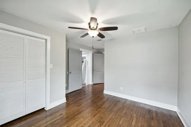 an empty room with wooden floor ceiling fan and windows