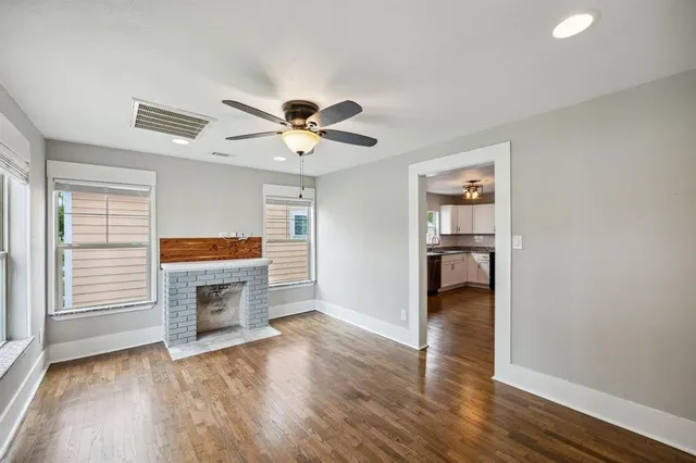 a view of a livingroom with a fireplace a ceiling fan and wooden floor