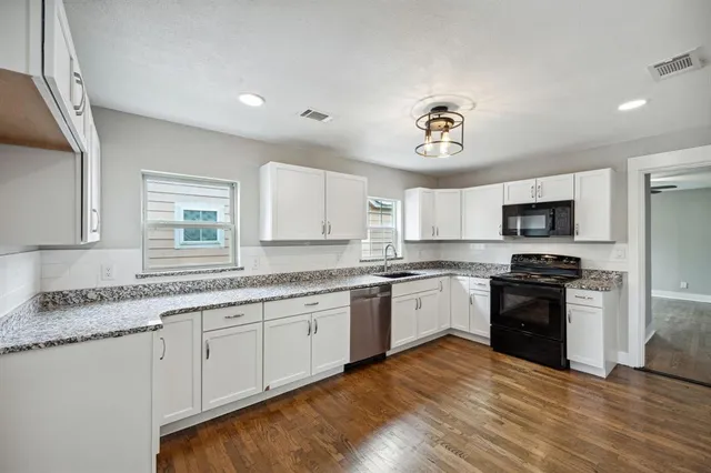 a kitchen with granite countertop a sink stainless steel appliances and cabinets