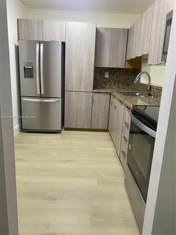 a kitchen with granite countertop a refrigerator and a sink