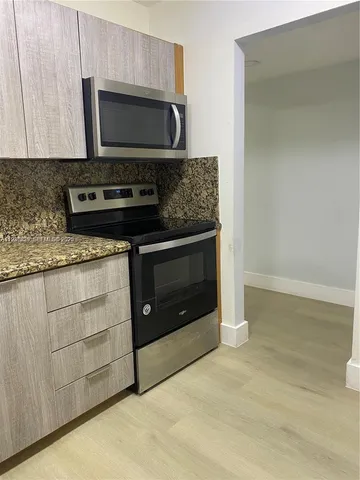 a kitchen with granite countertop a stove and a microwave with cabinets