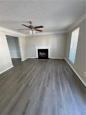 an empty room with wooden floor fireplace and windows