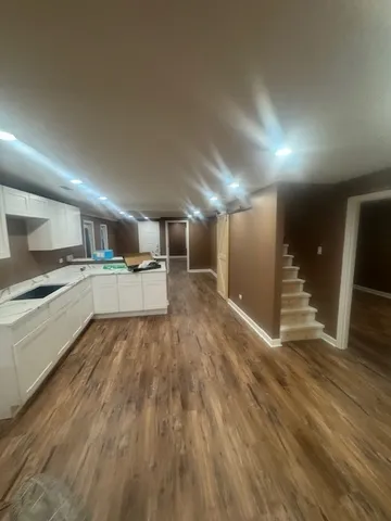 a large kitchen with a sink and dishwasher a stove top oven with wooden floor