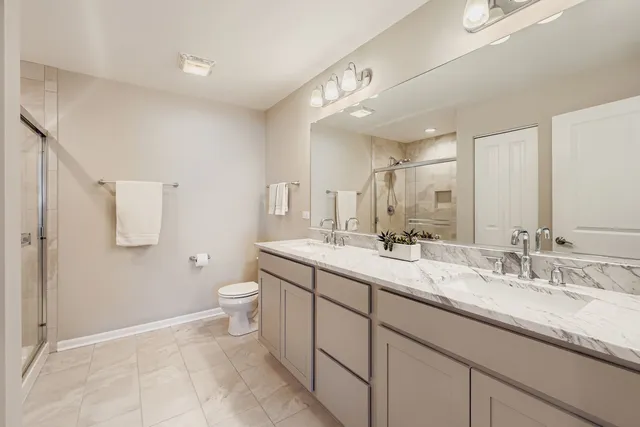 a spacious bathroom with a double vanity sink toilet and a mirror