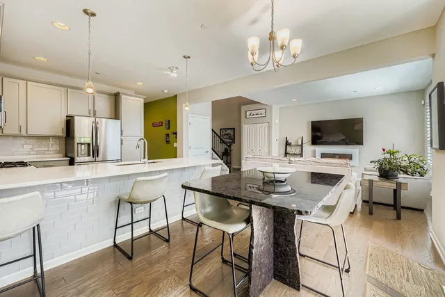 a kitchen with stainless steel appliances granite countertop a stove top oven a sink dishwasher a dining table and chairs with wooden floor