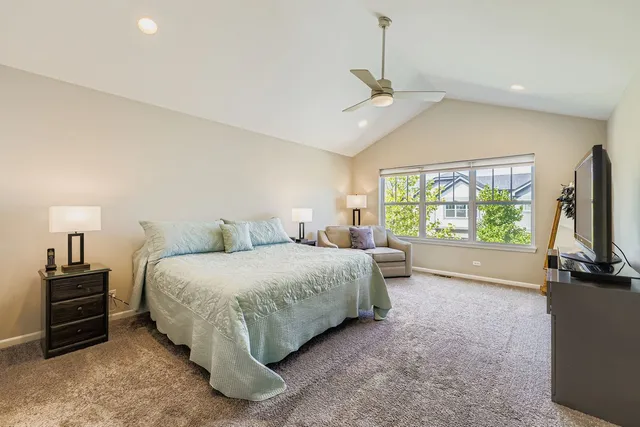 a spacious bedroom with a bed and a flat tv screen on the dresser