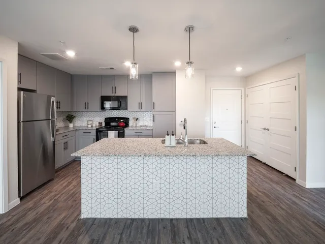 a large kitchen with stainless steel appliances granite countertop a stove a refrigerator a oven and a wooden floors