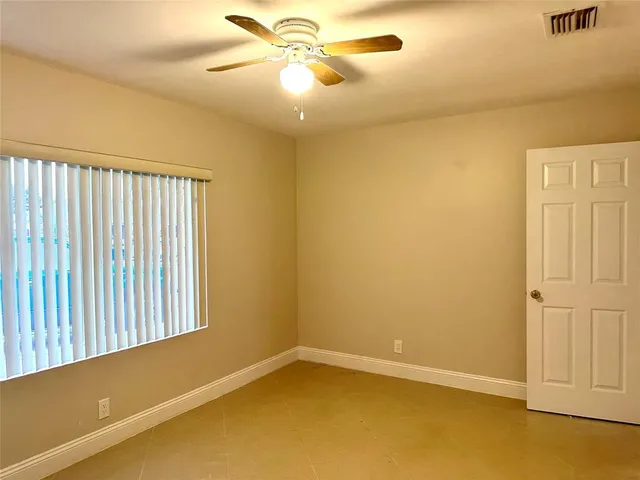 an empty room with a window and a ceiling fan