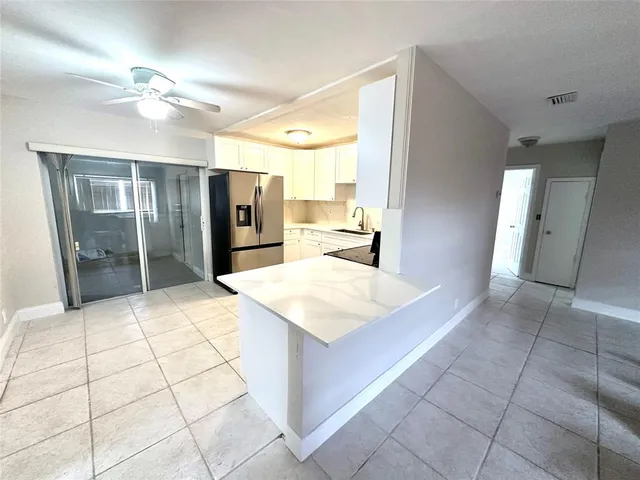 a large white kitchen with a sink and refrigerator
