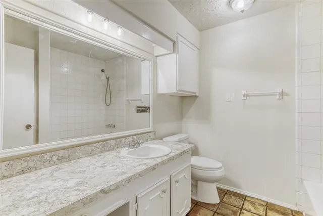 a bathroom with a granite countertop sink a toilet and a shower