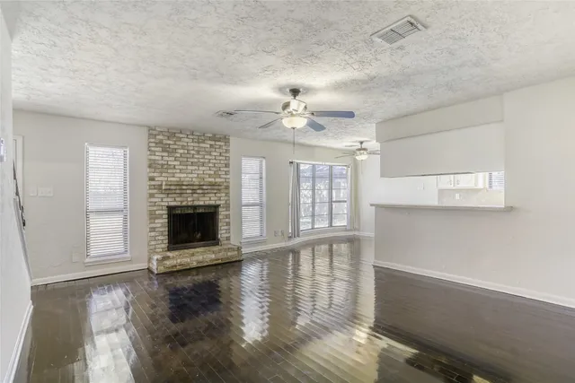 a view of an empty room with wooden floor fireplace and a window