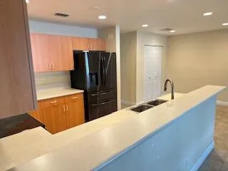 a kitchen with stainless steel appliances kitchen island granite countertop a refrigerator and a sink