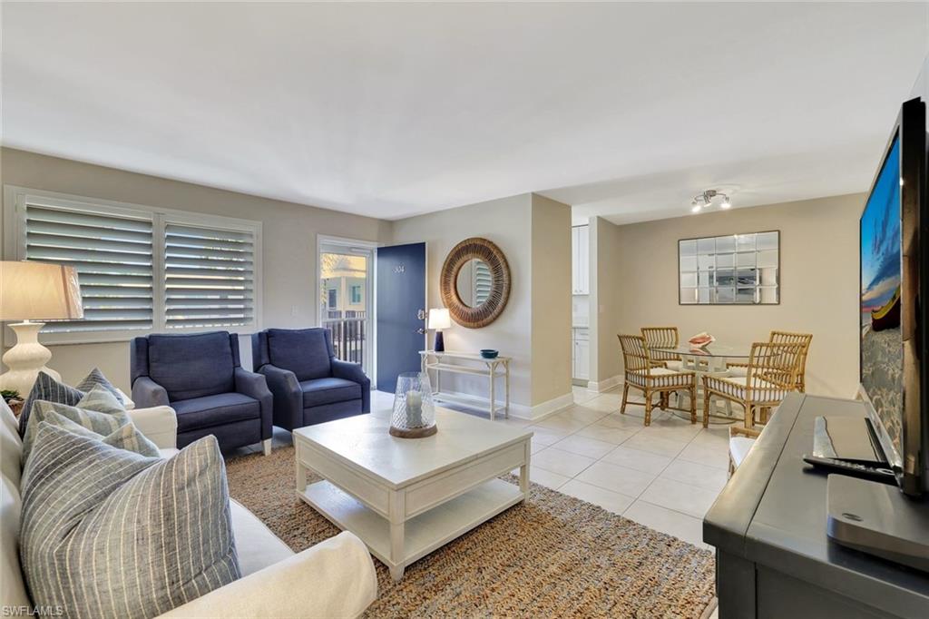 766 Central Avenue, Unit 304 Naples, FL 34102 - Photo 11 of 29 a living room with furniture a rug potted plant and a window