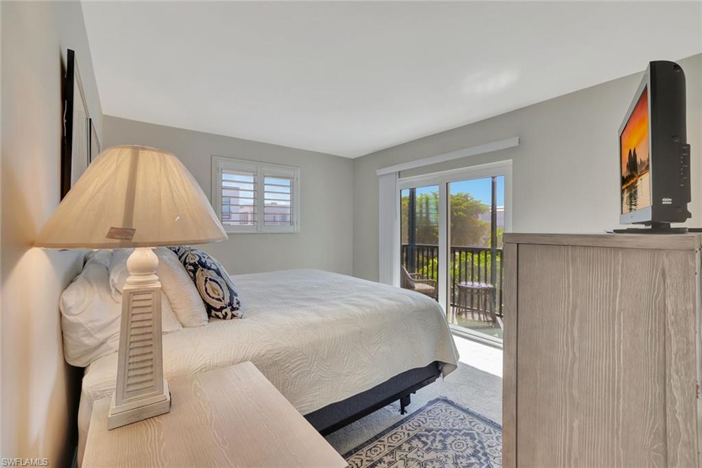 766 Central Avenue, Unit 304 Naples, FL 34102 - Photo 16 of 29 a bedroom with a bed lamp and window