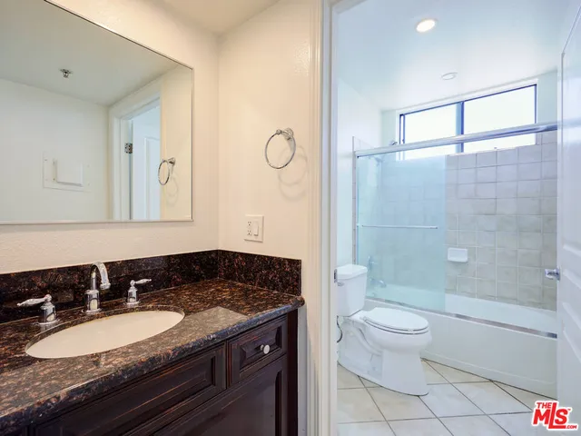 a bathroom with a granite countertop sink a toilet a mirror and shower