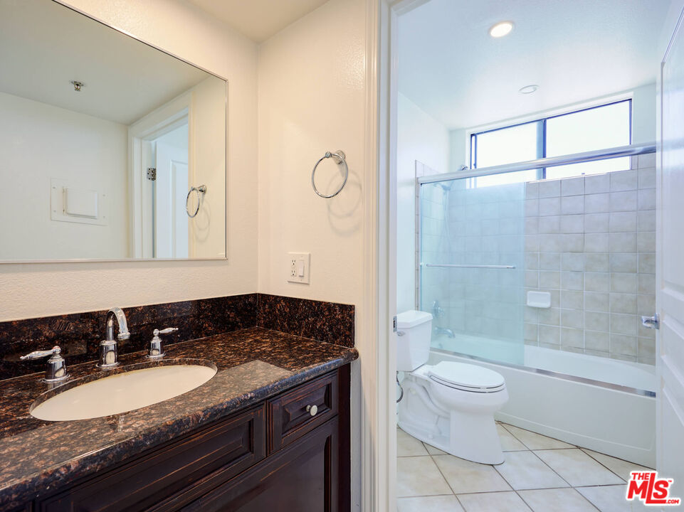 7320 Hawthorn Avenue, Unit 222 Los Angeles, CA 90046 - Photo 19 of 33 a bathroom with a granite countertop sink a toilet a mirror and shower