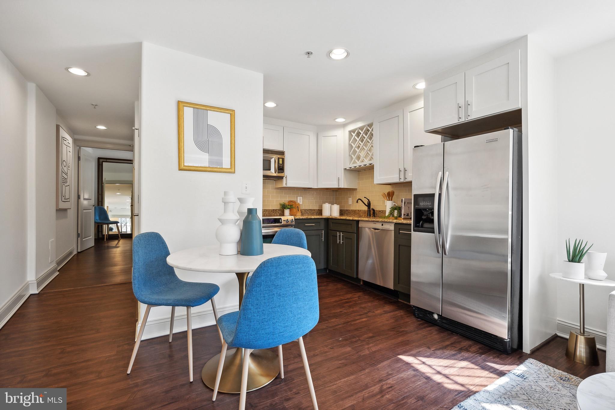 1354 Euclid Street Northwest, Unit 101B Washington, DC 20009 - Photo 6 of 15 a kitchen with stainless steel appliances granite countertop a refrigerator a stove a sink a dining table and chairs with wooden floor