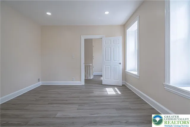 a view of an empty room with wooden floor and window