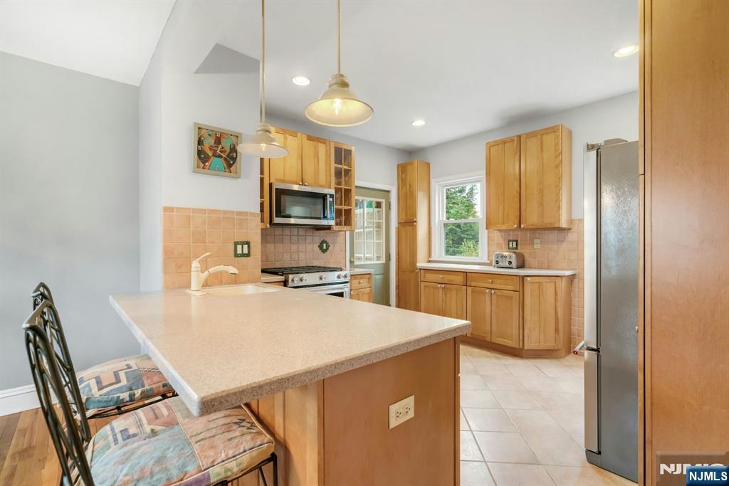 409 Warren Avenue Ho-Ho-Kus, NJ 07423 - Photo 8 of 23 a kitchen with a refrigerator a stove a sink dishwasher with a dining table and chairs