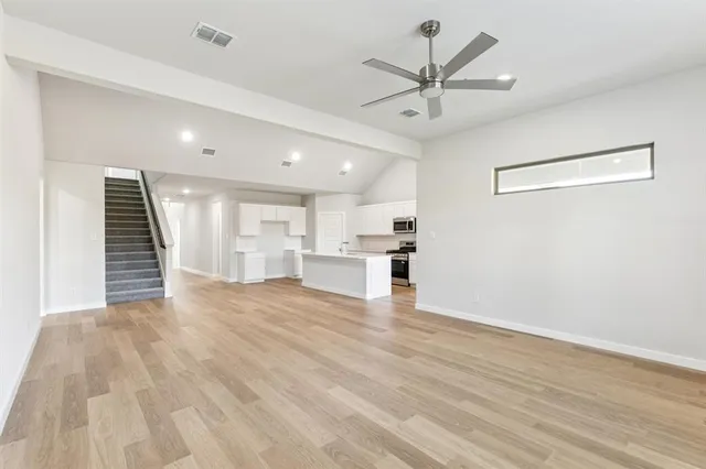 a view of empty room with wooden floor and ceiling fan