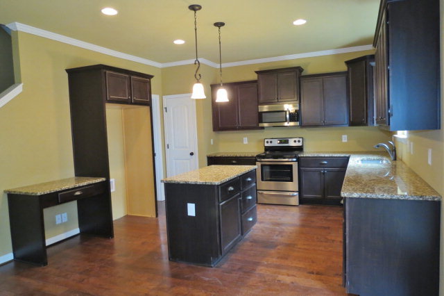 356 Walnut Grove Road Gray, GA 31032 - Photo 11 of 27 a kitchen with kitchen island granite countertop a refrigerator a sink and wooden cabinets