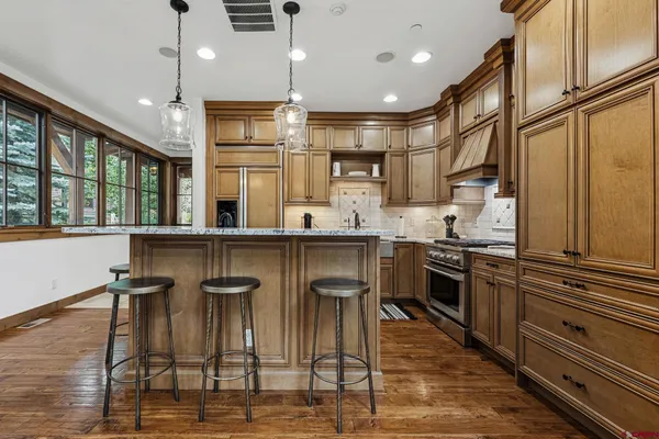 a kitchen with stainless steel appliances kitchen island granite countertop a table chairs and a refrigerator