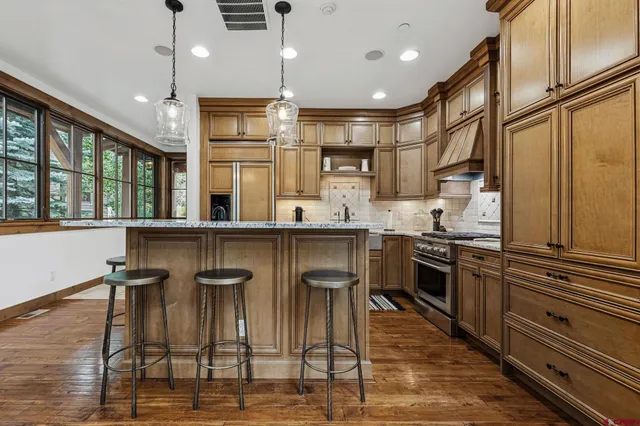 a kitchen with stainless steel appliances kitchen island granite countertop a table chairs and a refrigerator