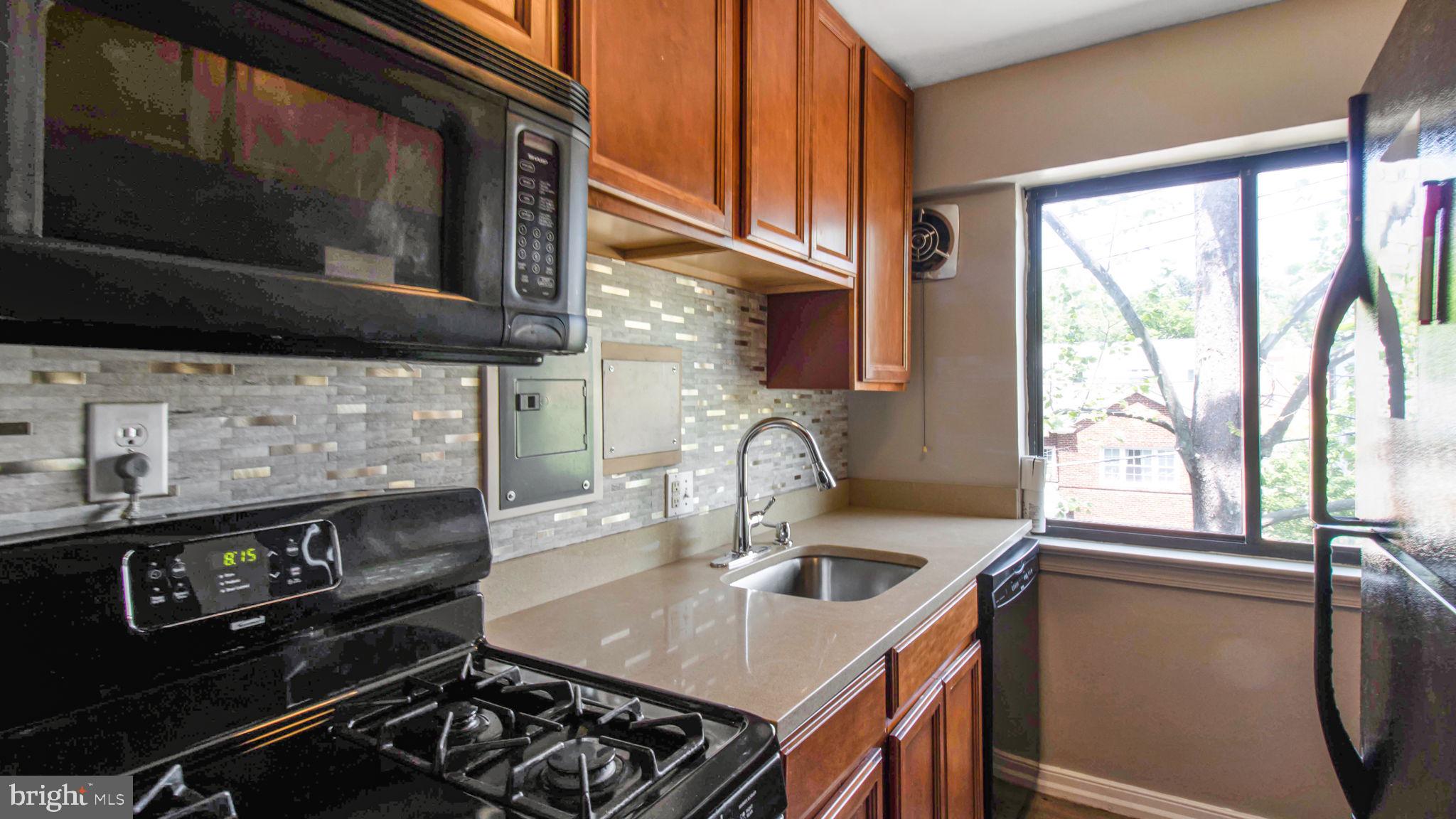 3901 Tunlaw Road Northwest, Unit 701 Washington, DC 20007 - Photo 4 of 17 a kitchen with a stove a sink and a microwave