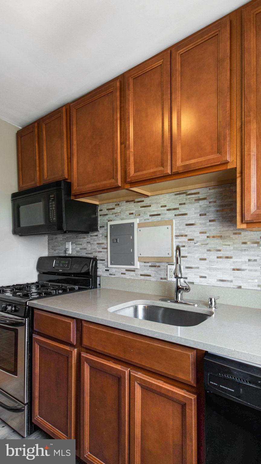 3901 Tunlaw Road Northwest, Unit 701 Washington, DC 20007 - Photo 6 of 17 a kitchen with granite countertop stainless steel appliances a sink stove and microwave