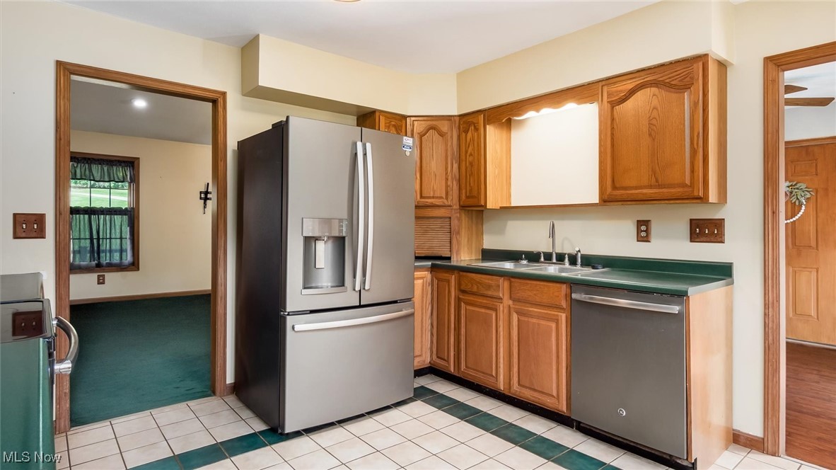 9910 Matchett Road Norwich, OH 43767 - Photo 13 of 48 Kitchen featuring appliances with stainless steel finishes, brown cabinetry, dark countertops, and light tile patterned floors